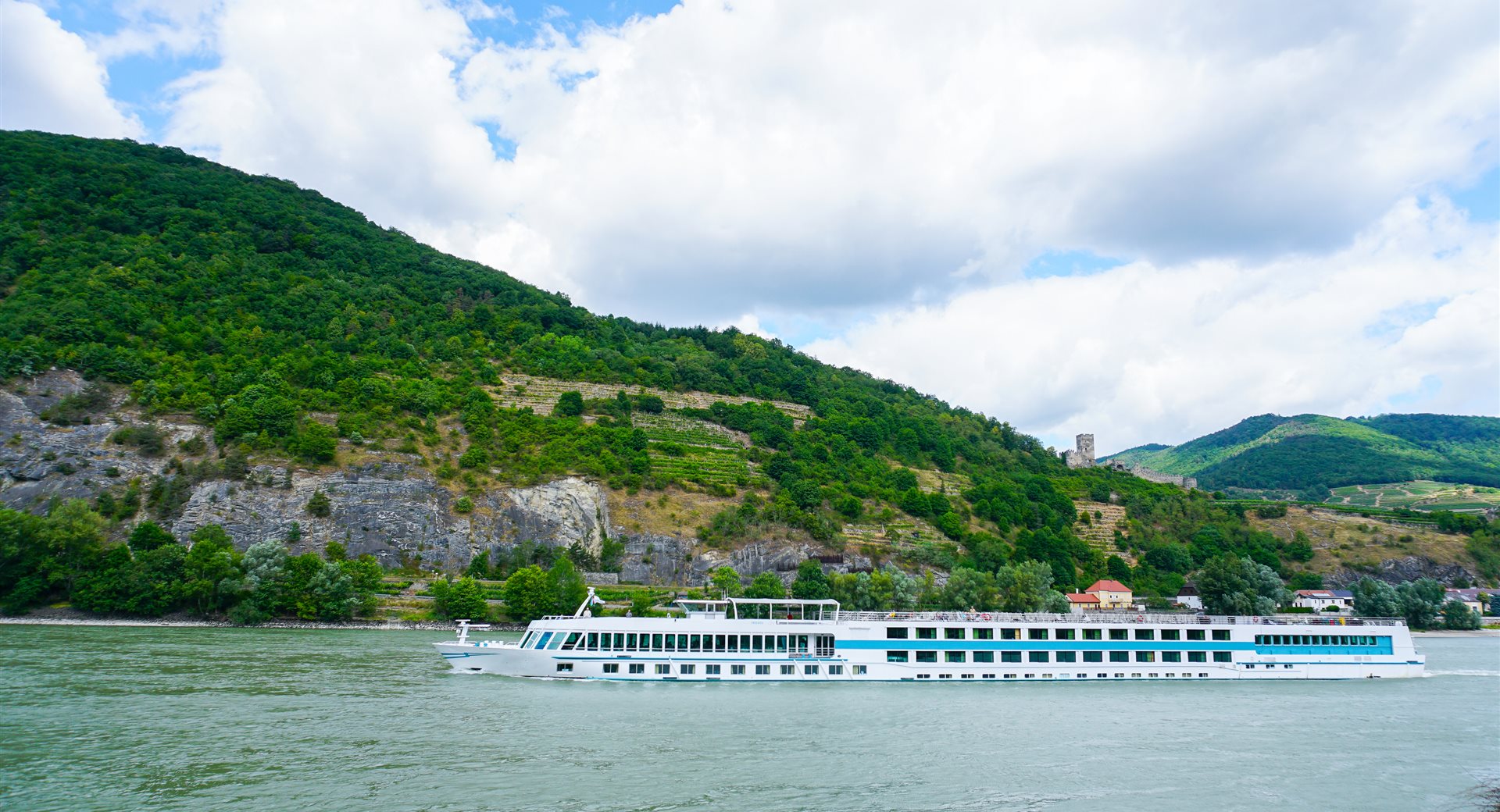 River cruise ship on the Danube below mountain scenery — river cruise deals